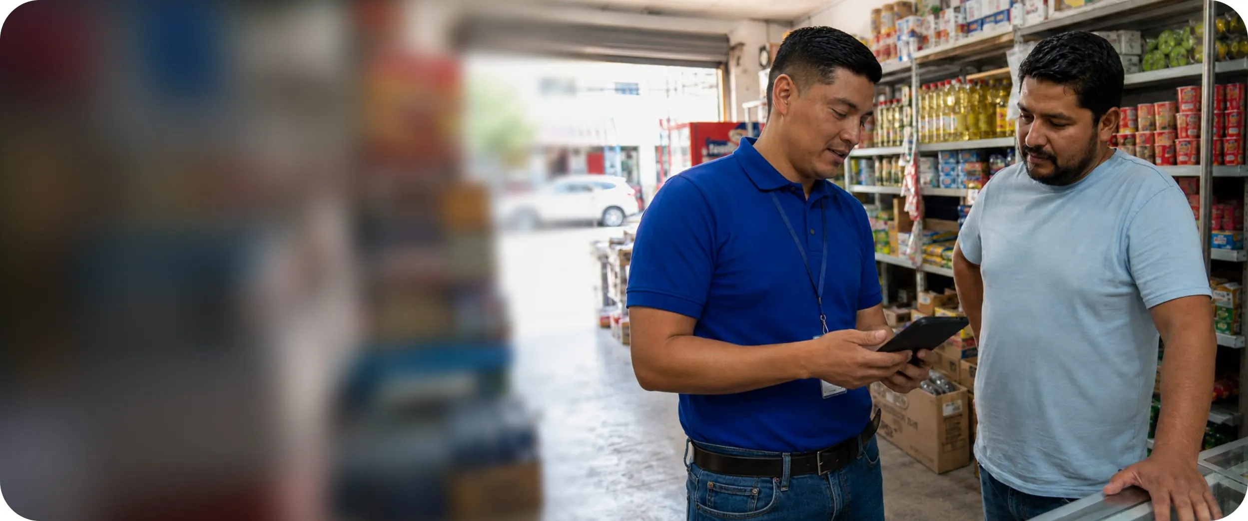 Un vendedor mostrando la aplicación de GU Trade al dueño de un almacén
